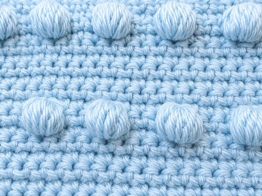 Close-up of crochet puff stitches and single crochet texture in a blue practice motif