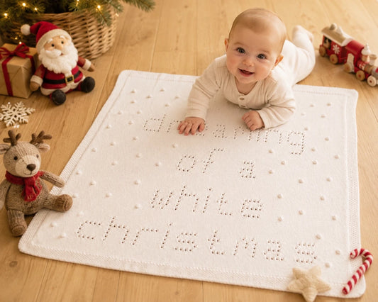 Baby enjoying tummy time on I'm Dreaming of a White Christmas baby blanket knitting pattern in a Christmas nursery