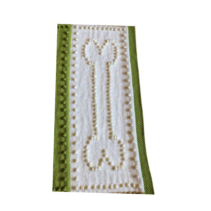 Close-up of cream and green dog bone panel on a knitted bobble stitch dog blanket with textured border detail