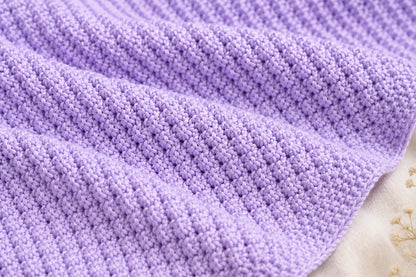 Close up of the lilac Blackberry stitch baby blanket showing the textured knitted stitch pattern and soft folds