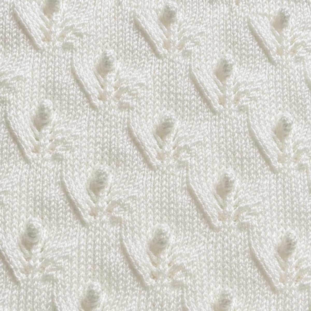 Elegant close up of white Budding Flowers baby blanket knitting pattern showing delicate floral lace and bobble stitch texture in soft ivory yarn