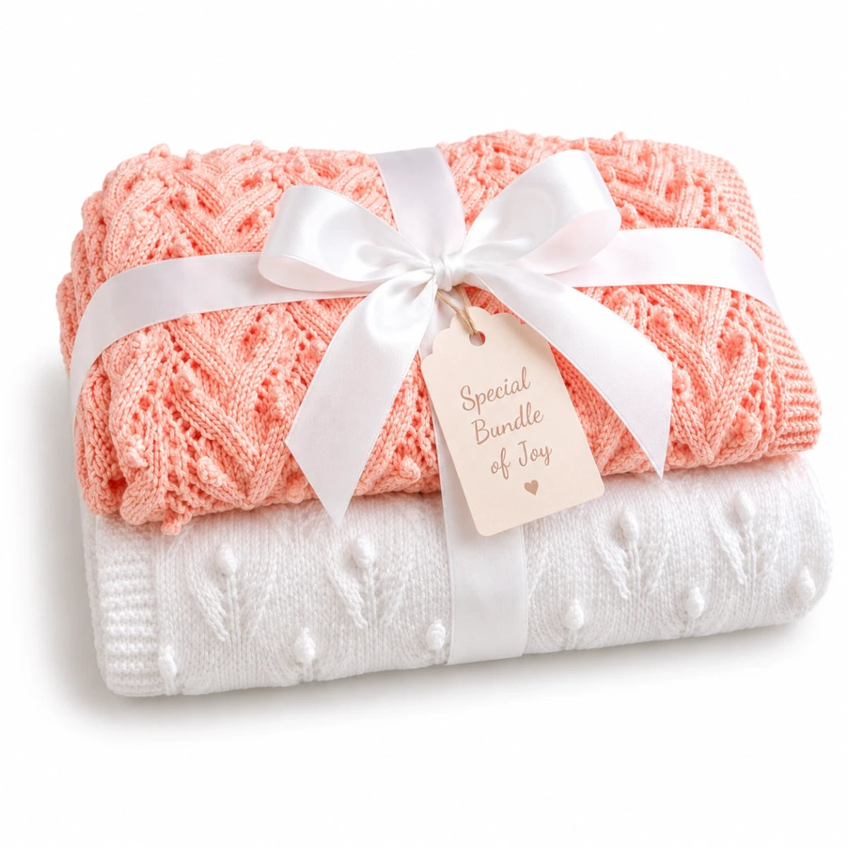 Gift wrapped peach and white baby blanket knitting pattern bundle with textured Plaited Bobbles and Budding Flowers stitch patterns tied with a white satin ribbon and soft cream Special Bundle of Joy tag on a white background