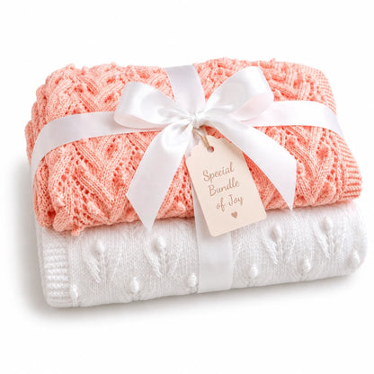 Gift wrapped peach and white baby blanket knitting pattern bundle with textured Plaited Bobbles and Budding Flowers stitch patterns tied with a white satin ribbon and soft cream Special Bundle of Joy tag on a white background