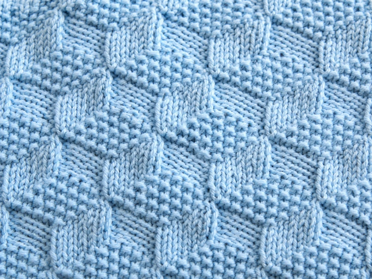 Elegant close up of blue Building Blocks baby blanket knitting pattern showing textured knit and purl geometric stitch detail in soft pastel yarn