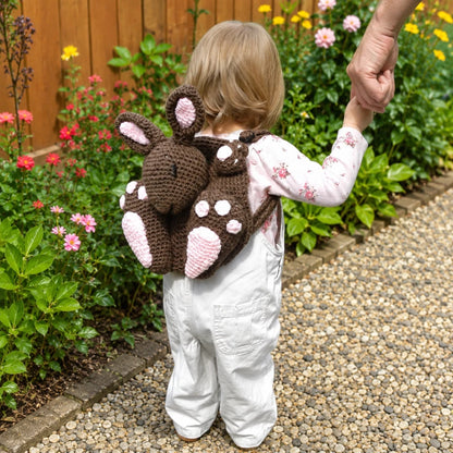 Toddler wearing bunny backpack crochet pattern in a garden showing the finished animal backpack design