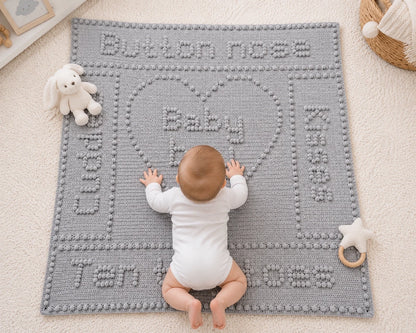 Baby enjoying tummy time on the grey Button Nose baby blanket crochet pattern in a bright nursery with soft white toys.