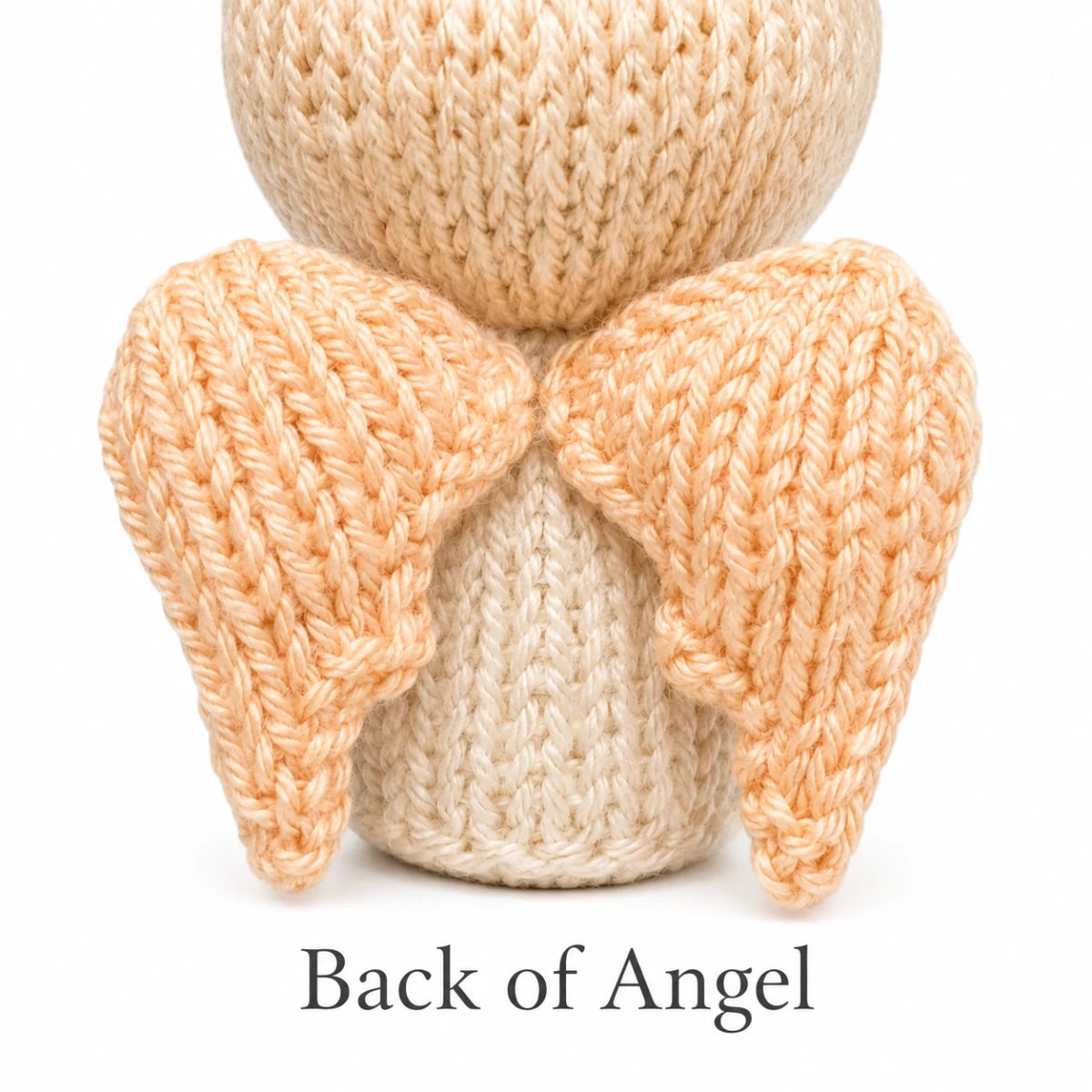 Back view of knitted angel Christmas decoration showing handmade wings and worked flat construction details.