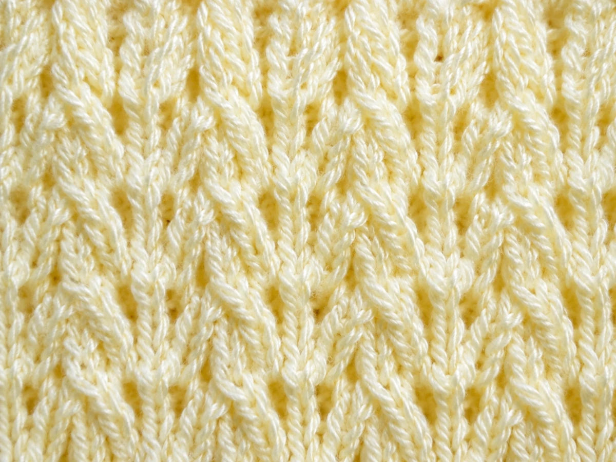 Elegant close up of the Corn Rows baby blanket knitting pattern showing soft pastel yellow textured knit stitches with repeating raised cable-style rows and delicate vertical detail