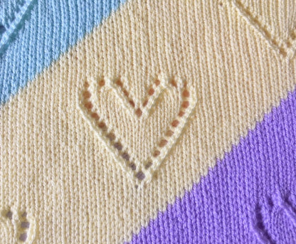 Close up of Diagonal Lace baby blanket knitting pattern showing pastel diagonal stripes with delicate lace heart stitch detail and soft knitted texture