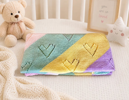 Folded pastel diagonal lace heart baby blanket knitting pattern styled in cosy nursery scene with soft knitted texture and heart eyelets