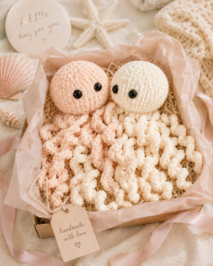 Pastel peach and cream jellyfish knitting pattern displayed in a handmade gift box with ribbon and seashell styling