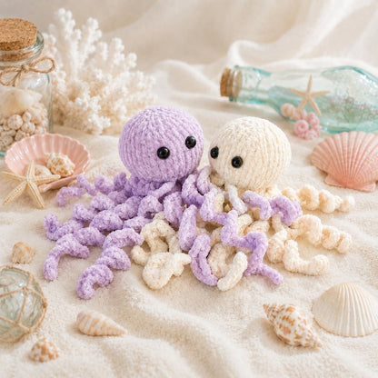 Pastel lilac and cream jellyfish soft toy knitting pattern in a cozy ocean-inspired seashell scene