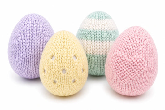 Four pastel knitted Easter eggs on a white background including striped, eyelet and textured egg designs from a free knitting pattern bundle by Peach Unicorn Designs