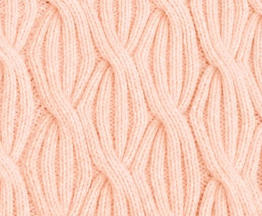 Close-up of Rainbow Waves baby blanket in soft peach colour showing repeating cable knitting texture and stitch definition