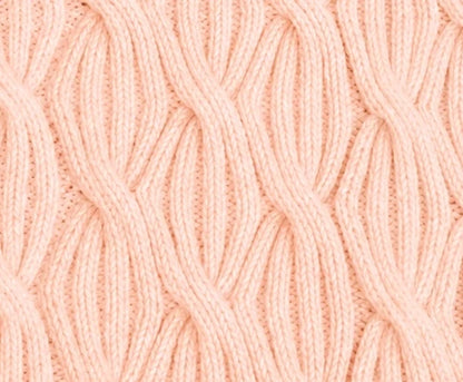 Close-up of Rainbow Waves baby blanket in soft peach colour showing repeating cable knitting texture and stitch definition