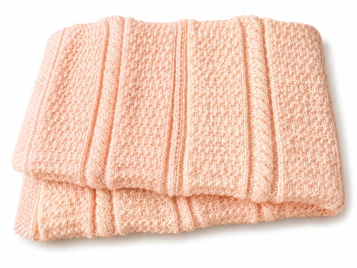 Folded soft peach Granite Cable baby blanket made using the free knitting pattern