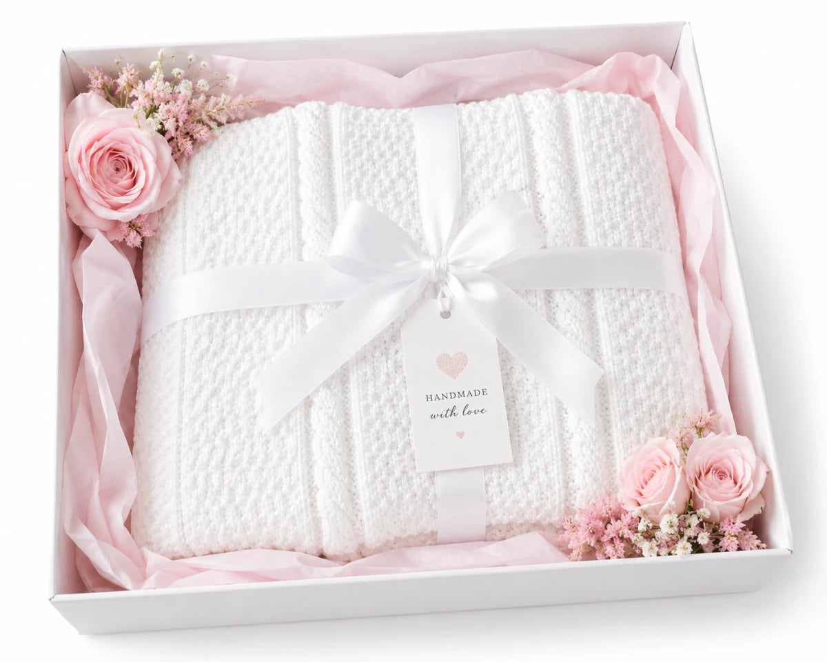 White Granite Cable baby blanket presented in a gift box with soft pink tissue paper and flowers
