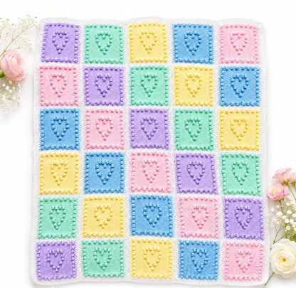 Heart Squares baby blanket knitting pattern with pastel bobble heart squares in pink, blue, yellow, mint and lilac on a white background with soft flowers and gentle shadow detail