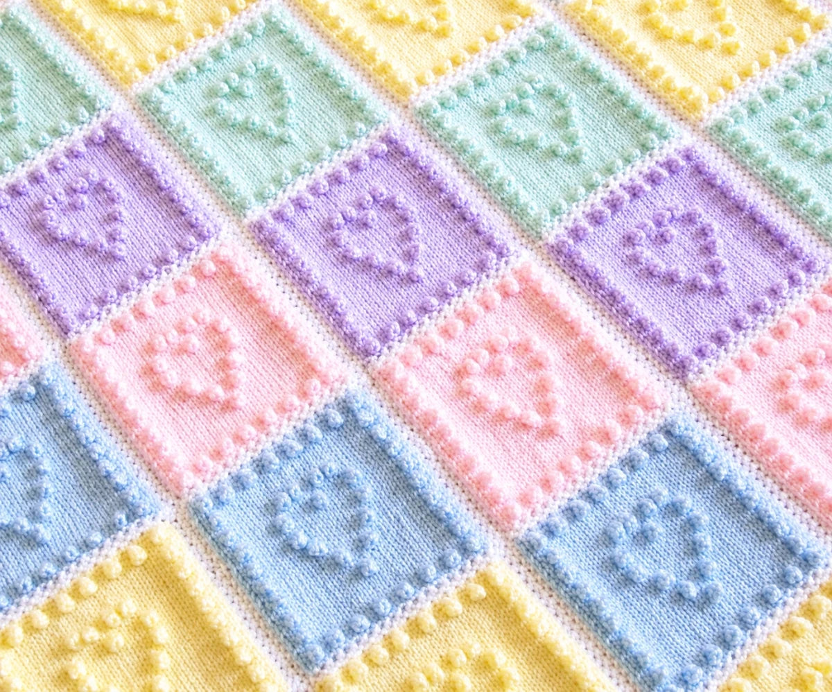 Close-up of Heart Squares baby blanket knitting pattern with pastel bobble-stitch heart squares
