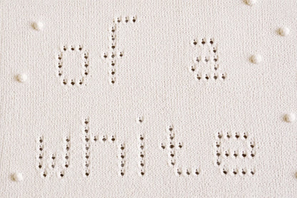 Close-up of the lace knitting detail from the I'm Dreaming of a White Christmas baby blanket knitting pattern showing eyelet lettering and textured bobble accents.