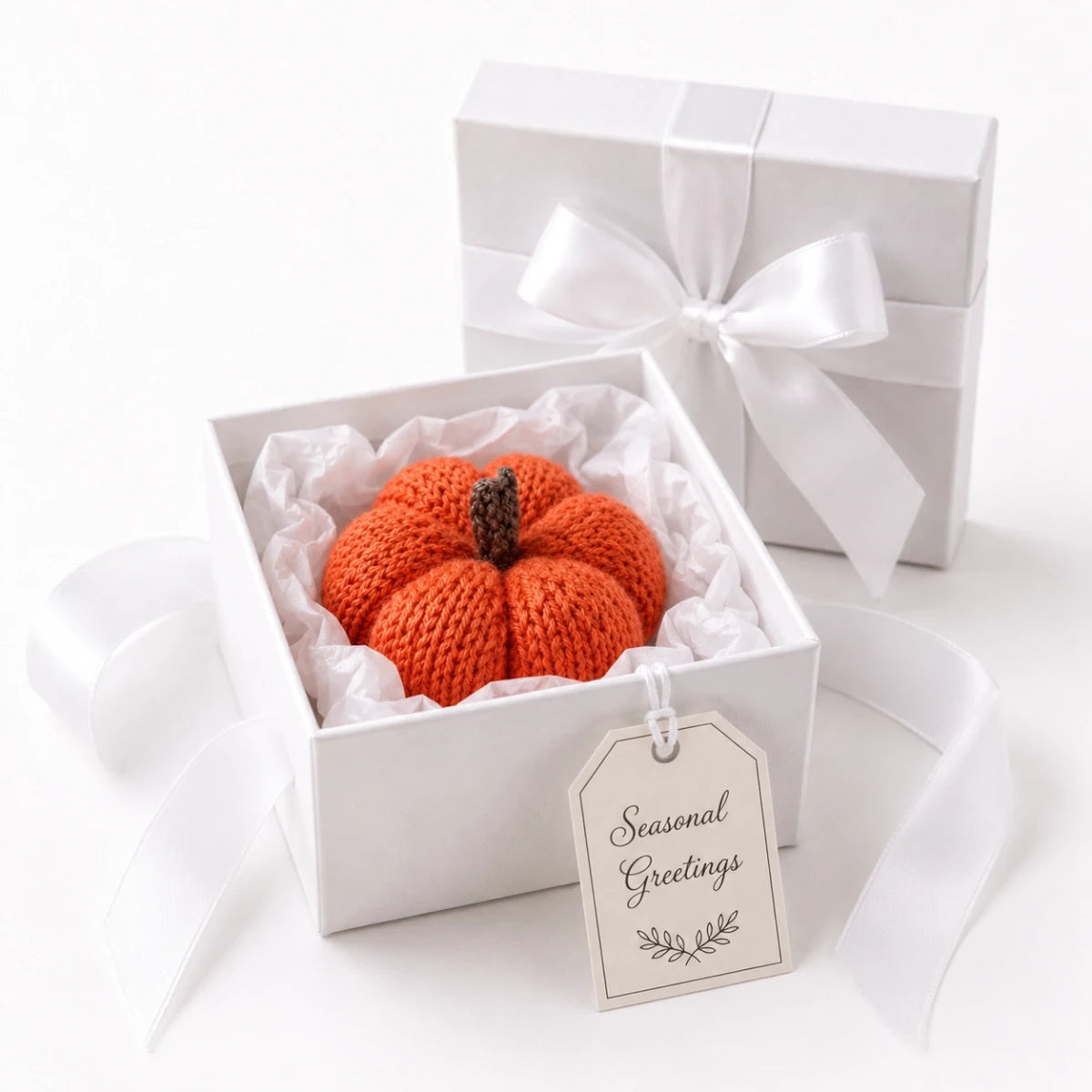 Knitted pumpkin Halloween decoration presented in a white gift box with tissue paper, white ribbon bow and Seasonal Greetings gift tag