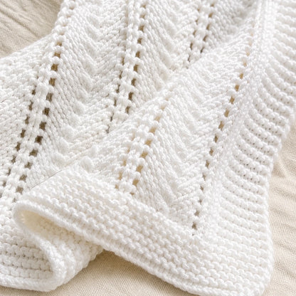 Close-up texture of white lace baby blanket knitting pattern featuring diagonal lace stitches and garter stitch edging