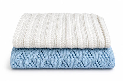 Folded white and blue lace baby blankets stacked together on a white background featuring the Lacy Lanes and Lacy Triangles knitting pattern bundle for beginners.
