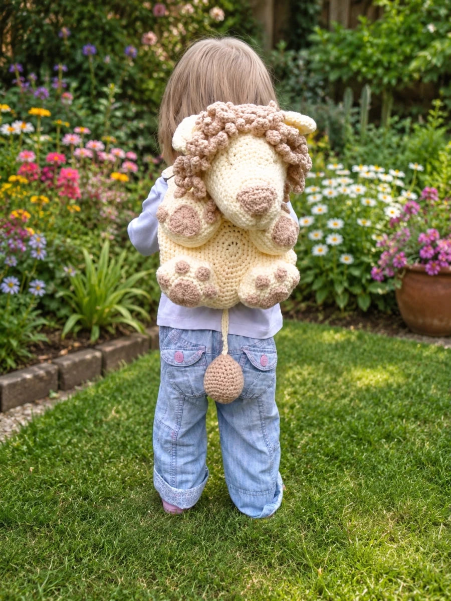 Toddler wearing lion backpack crochet pattern in a garden showing the finished animal backpack design