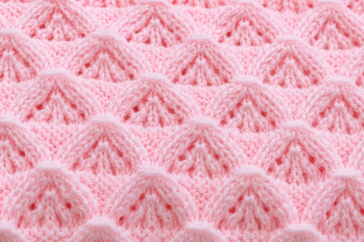 Elegant close up of pink Little Peaks baby blanket knitting pattern showing raised textured peak stitch detail in soft pastel yarn