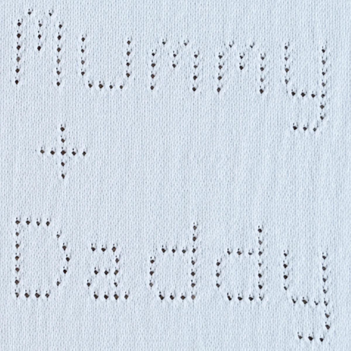 Close-up of eyelet lettering reading  Mummy plus Daddy on a knitted baby blanket knitting pattern