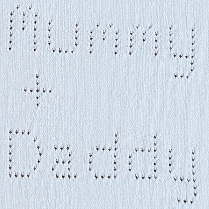 Close-up of eyelet lettering reading  Mummy plus Daddy on a knitted baby blanket knitting pattern