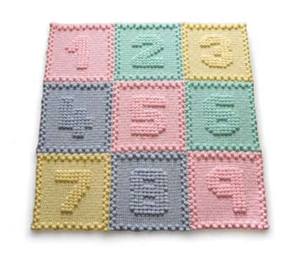 Pastel Numbers Motifs crochet baby blanket with raised puff stitch numbers on a white background.