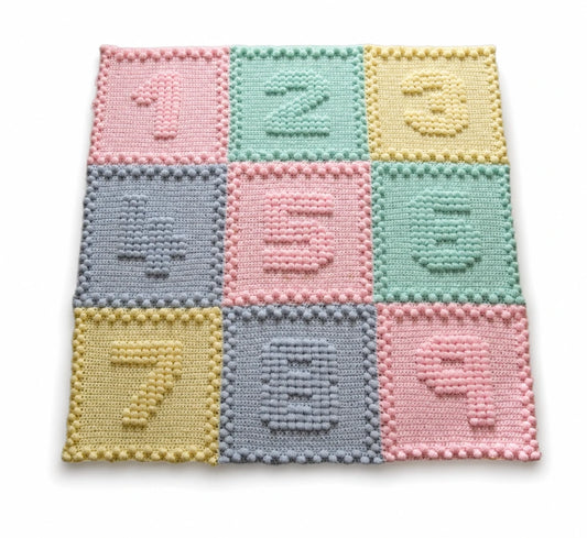 Pastel Numbers Motifs crochet baby blanket with raised puff stitch numbers on a white background.