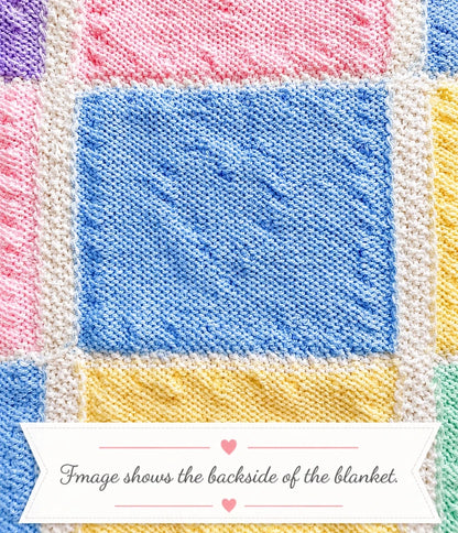 Close up of the backside of a pastel heart baby blanket showing the reverse texture of the knitted bobble heart squares with decorative banner text saying image shows the backside of the blanket.