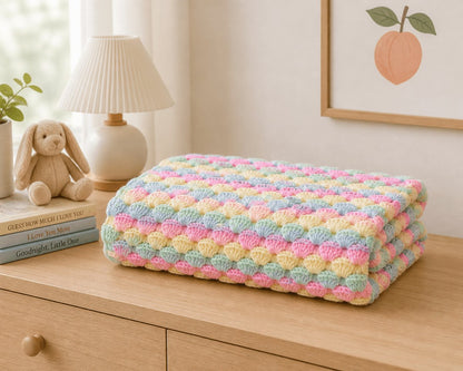 Pastel crochet shell stitch baby blanket styled in a soft neutral nursery