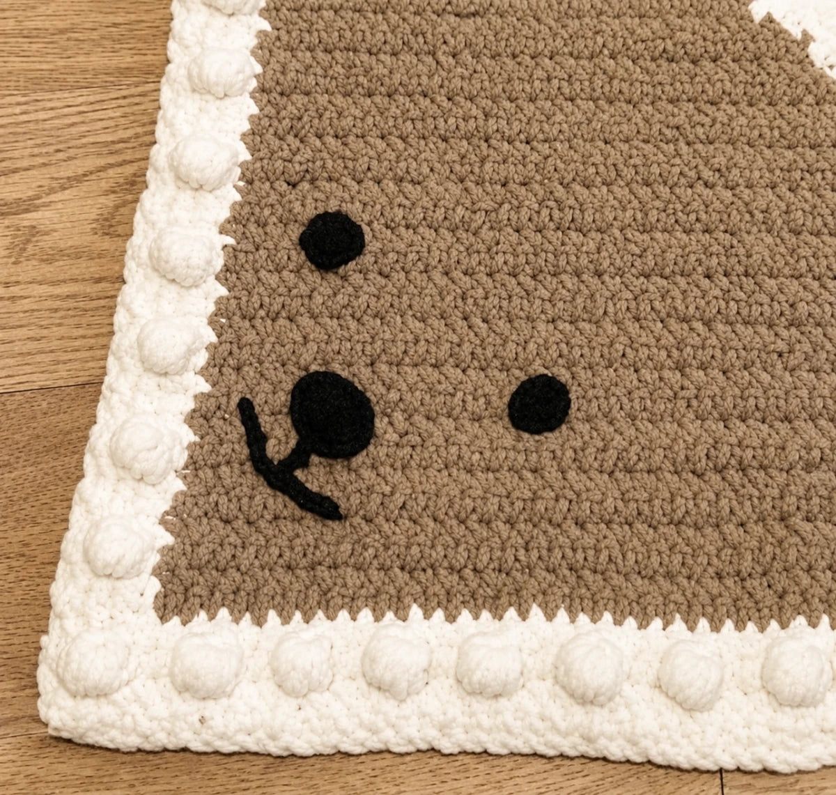 Close-up of the bear face and textured bobble border on the Peekaboo Baby Blanket crochet pattern.