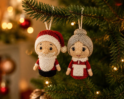 Knitted Santa and Mrs Claus Christmas tree decorations hanging from a festive branch with twinkling lights