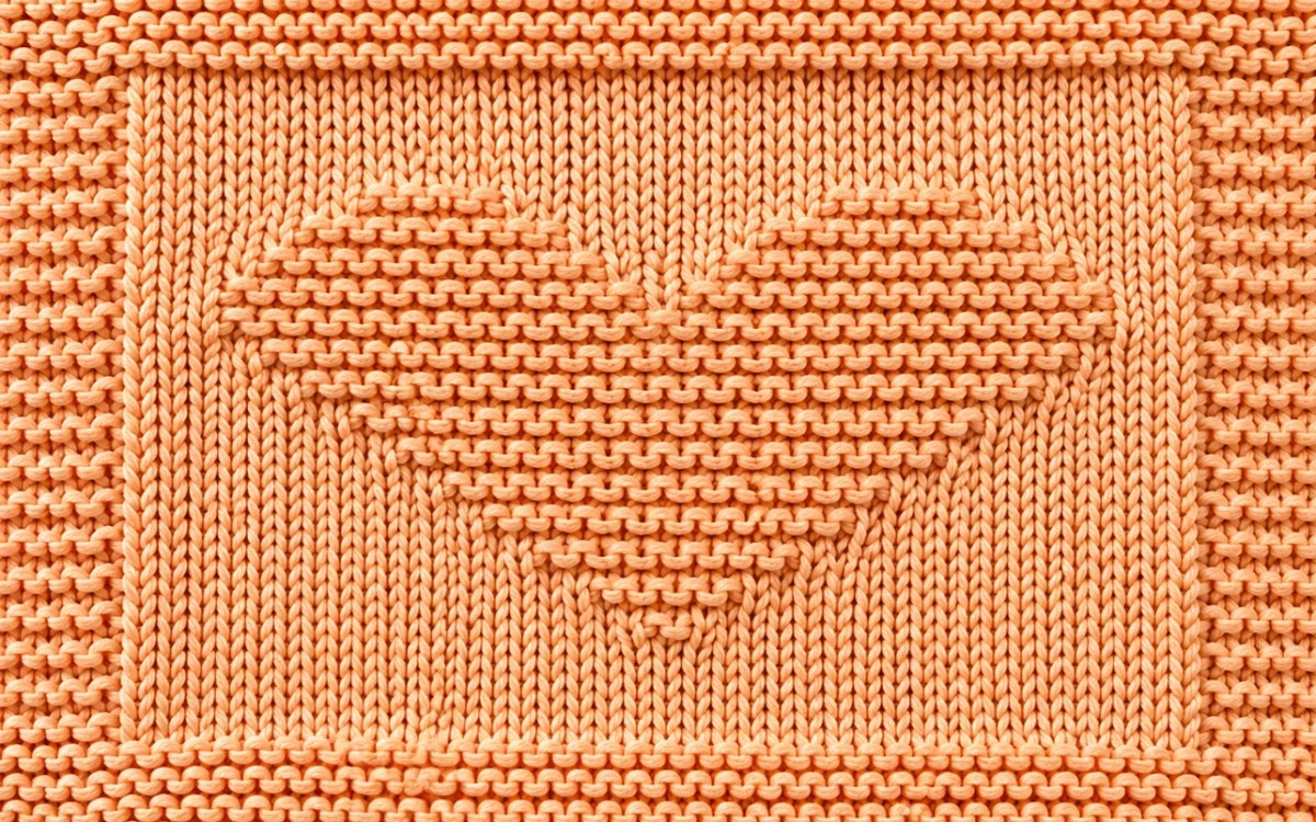 Close-up of the Simple Hearts Baby Blanket showing the garter stitch heart motif and textured knitted border