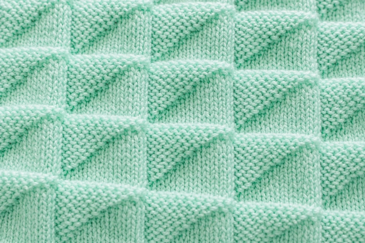 Elegant close up of the mint green simple triangles baby blanket showing the raised geometric knit stitch texture