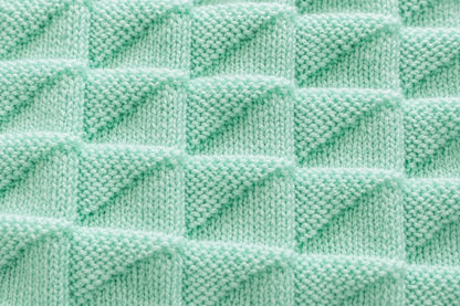 Elegant close up of the mint green simple triangles baby blanket showing the raised geometric knit stitch texture