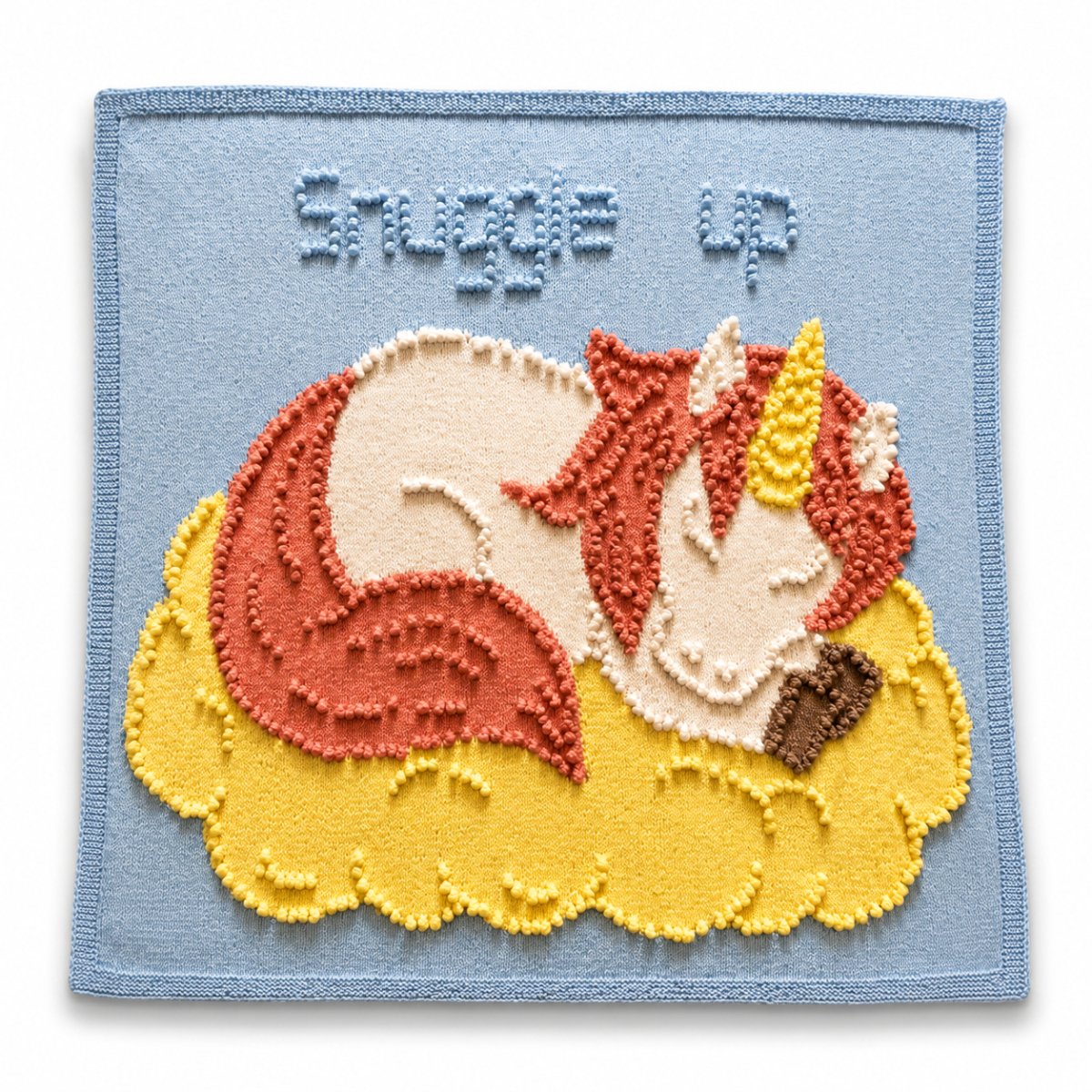 Sleeping Peach Unicorn toddler blanket knitting pattern laid flat on a white background with soft shadow and textured unicorn design for nursery décor
