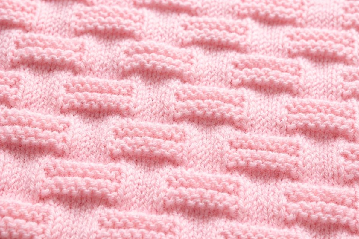 Elegant close up of soft pink Stepping Stones baby blanket knitting pattern showing raised knit and purl textured stitch detail