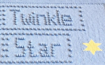 Close-up of Twinkle Twinkle Little Star knitted baby blanket showing bobble stitch lettering and intarsia star detail
