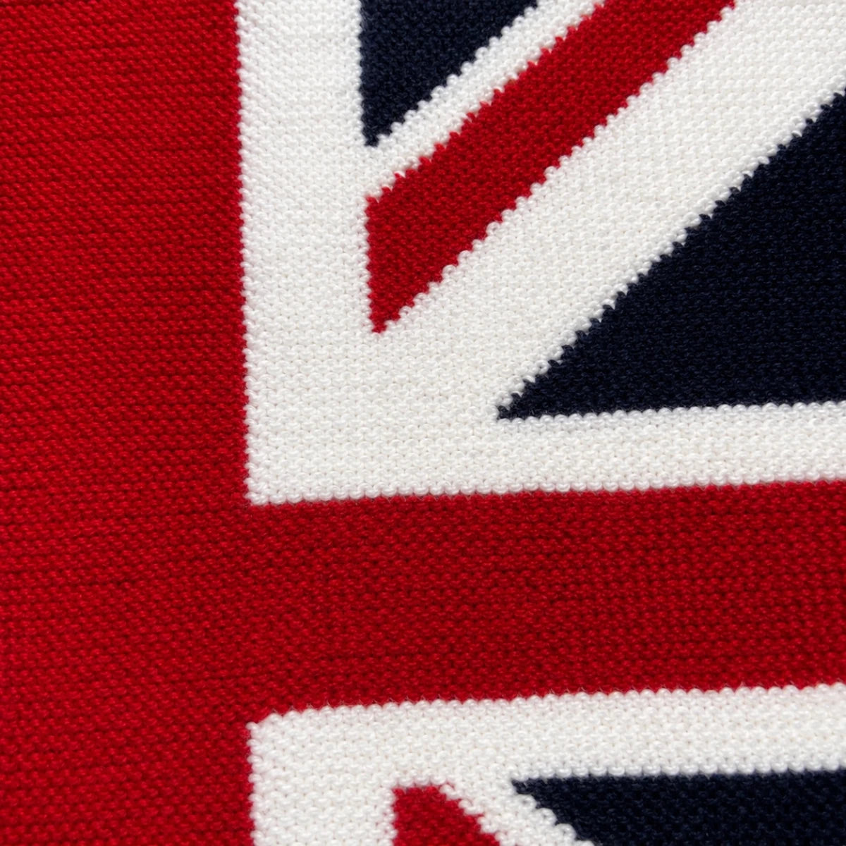 Close-up of the Union Jack Flag Lap Blanket knitting pattern showing the intarsia colourwork and stitch detail in red, white and navy yarn.